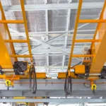 Overhead crane and hook inside factory building for lifting work.